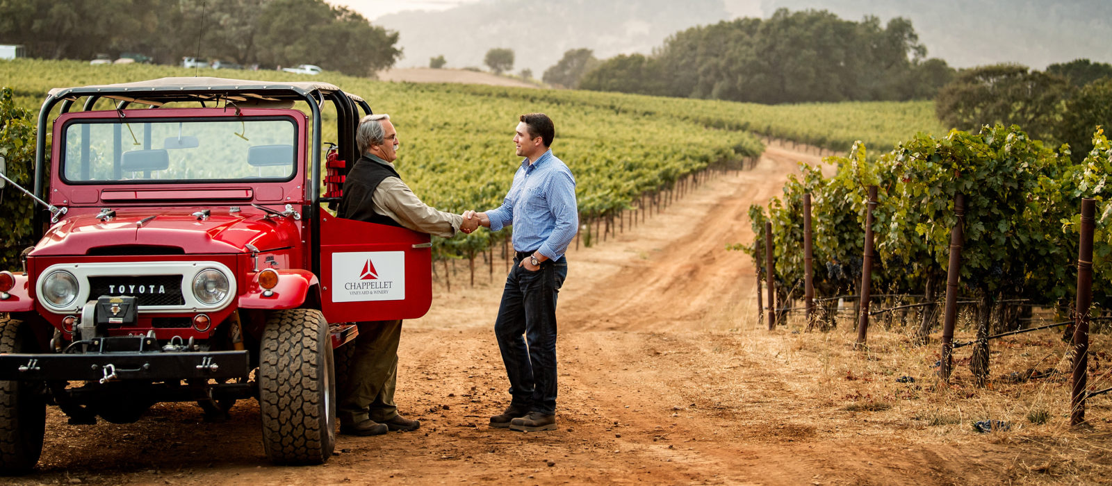 client and loan officer shaking hands in a vineyard