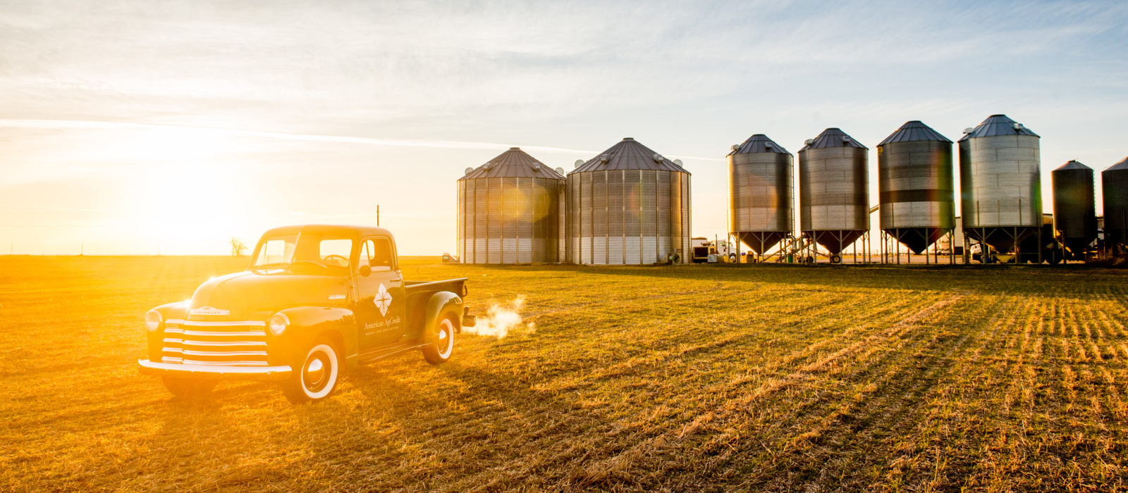 American Agcredit truck in front of silos at sunset