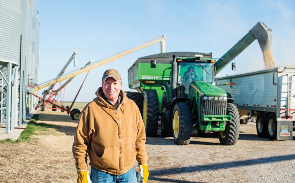 farmer standing in front of farm equipment and silo