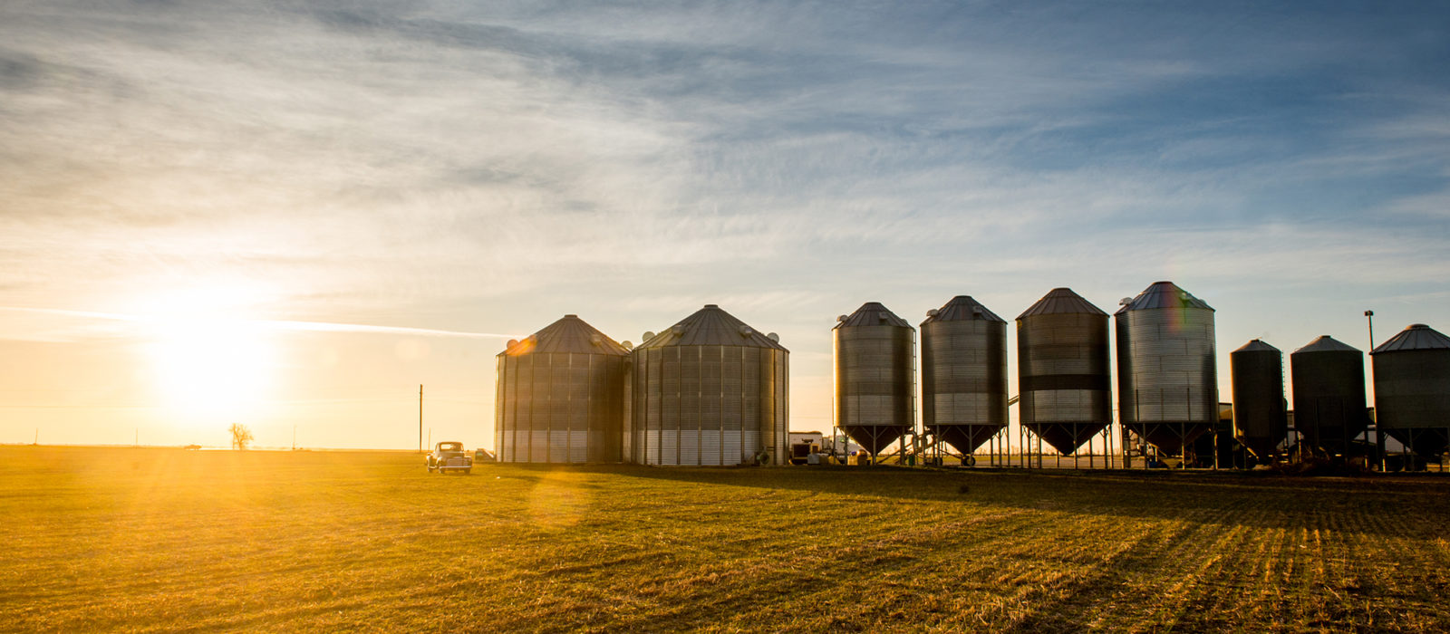 American AgCredit truck from a distance in front of silos at sunset