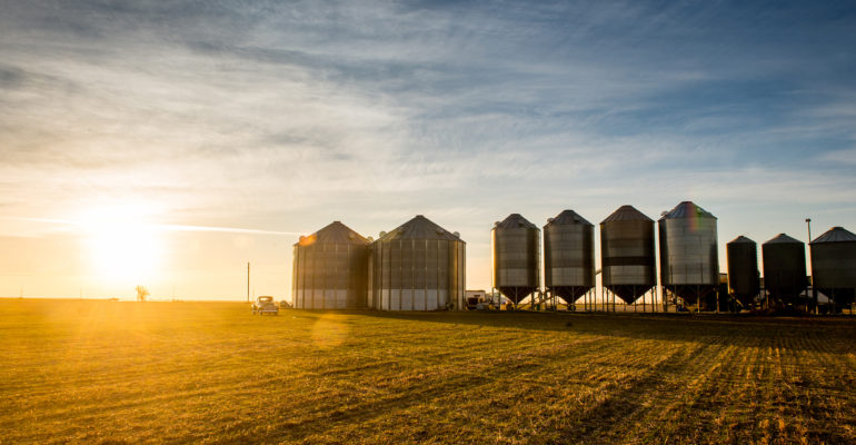 American AgCredit truck from a distance in front of silos at sunset