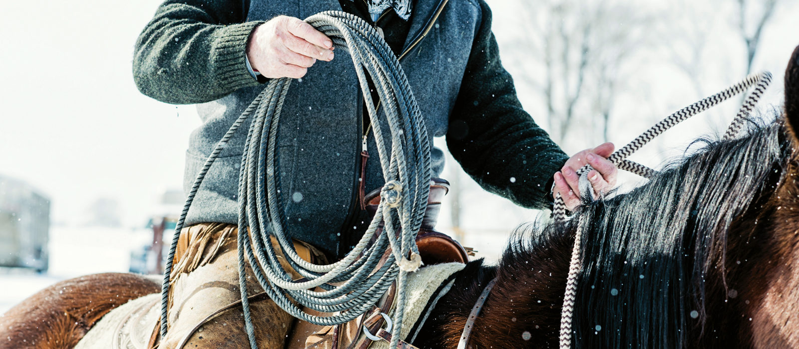 closeup of rancher on horseback with also in the snow