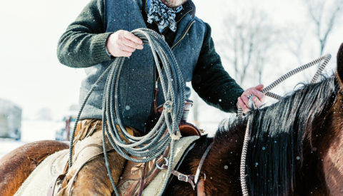 closeup of rancher on horseback with also in the snow