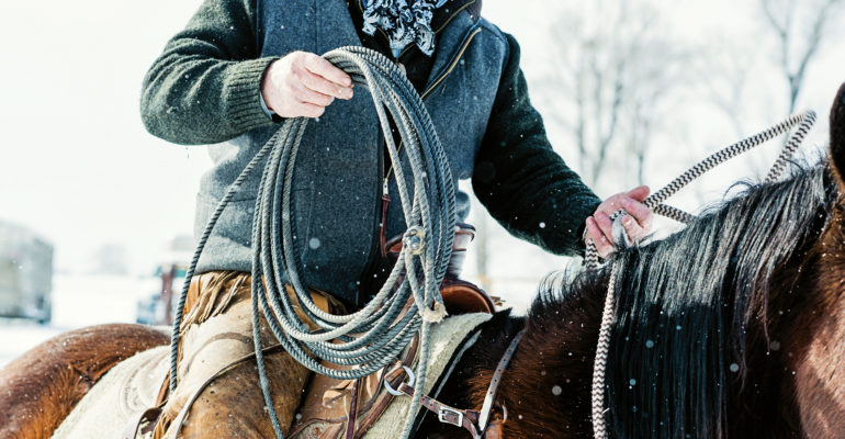 closeup of rancher on horseback with also in the snow