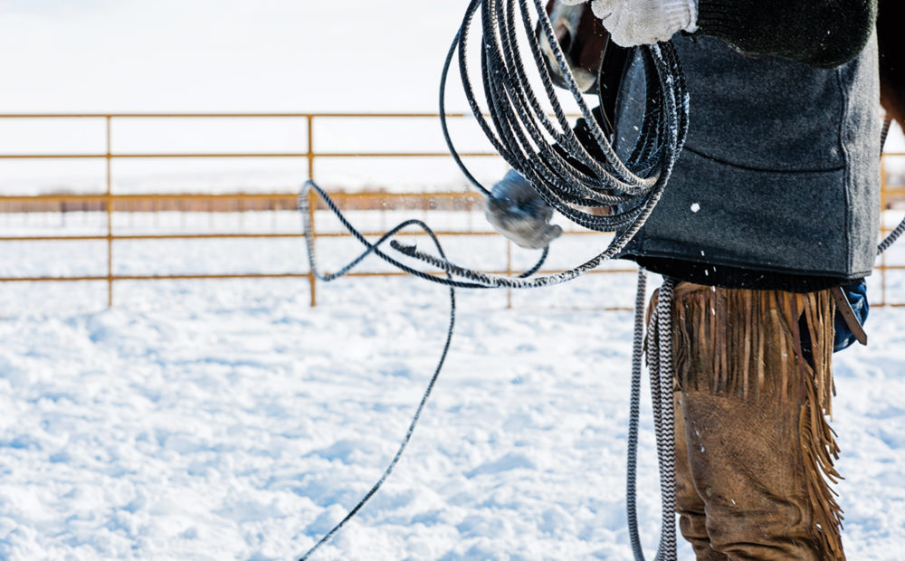 detail of rancher in chaps with lasso in the snow